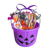 Purple Halloween candy bucket filled with treats on a white background