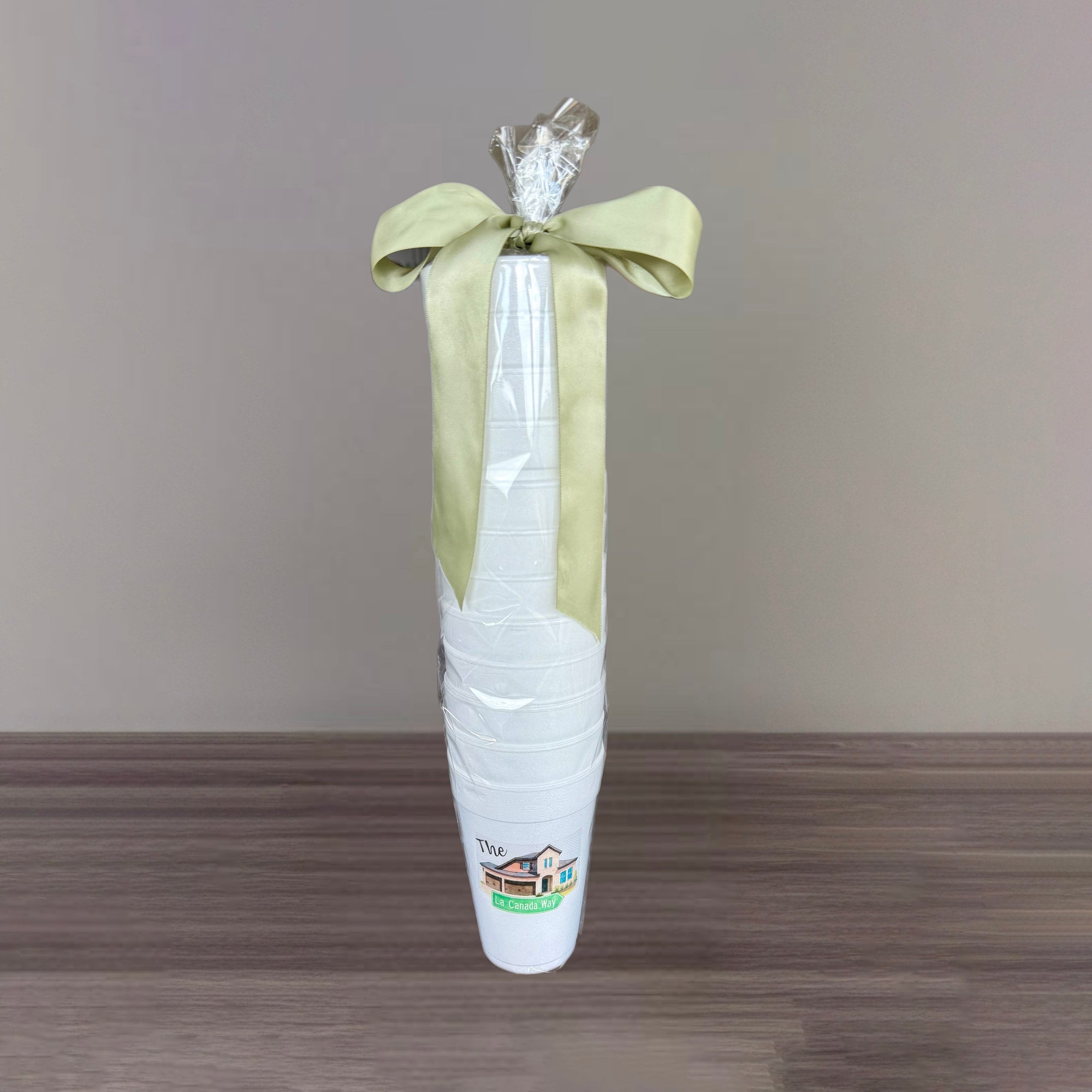 White cups with a green bow on a wooden surface and gray background